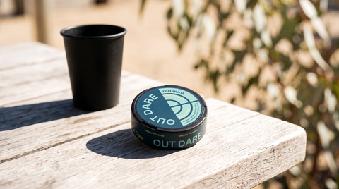 Caffeine pouch can resting on a sun-bleached timber table in bright outdoor Australian midday light