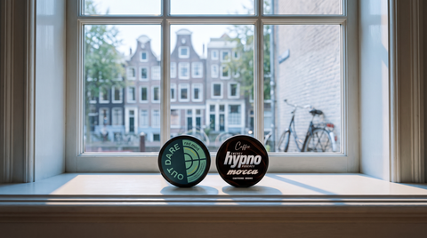 Two caffeine pouch cans on a white Dutch apartment windowsill overlooking a blurred canal street