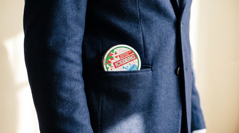 Small round nicotine pouch can discreetly tucked into a navy blazer breast pocket