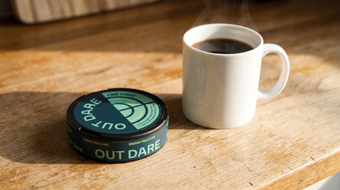 Round flat caffeine pouch can resting beside a mug of black coffee on a morning kitchen counter
