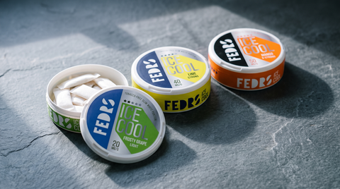 Three FEDRS nicotine pouch cans with different-coloured labels arranged on a grey slate worktop