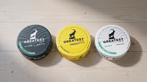 Three GREATEST nicotine pouch cans in a row on pale Nordic pine, showing Light, Lemonade and Strong variants