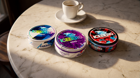 Three Iceberg nicotine pouch cans arranged on a marble café-style tabletop