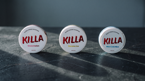 Three KILLA nicotine pouch cans in a row on a dark soapstone worktop in raking winter light