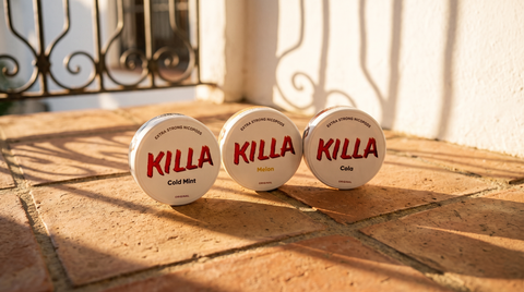 Three KILLA nicotine pouch cans with branded lids facing the camera on terracotta tiles