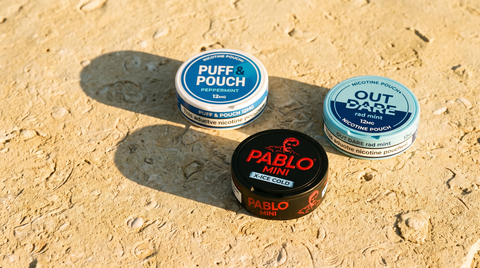 Three nicotine pouch cans resting on pale golden limestone in warm Mediterranean afternoon light