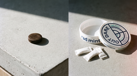 Dark snus tobacco portion beside an open OutDare nicotine pouches can with white pouches on concrete
