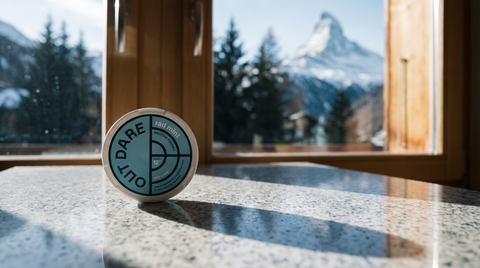 OUTDARE nicotine pouch can on granite worktop with blurred Swiss alpine mountain view