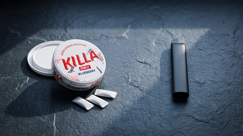 Open nicotine pouch can showing white pouches beside a vape pen on dark slate