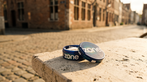 Nicotine pouch cans casting shadows on a stone café table in a Belgian street setting