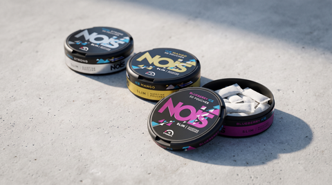 Three NOIS nicotine pouch cans in different flavours arranged side by side on pale concrete