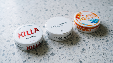 Three nicotine pouch cans from different brands lined up on pale terrazzo as nootropic alternatives