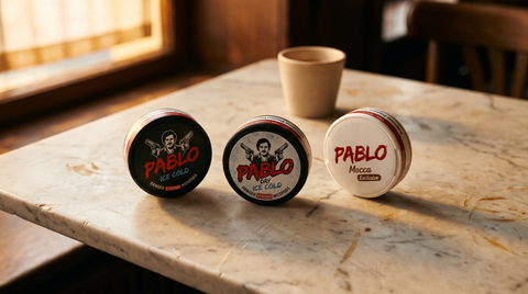 Three Pablo Mini nicotine pouch cans standing on a worn marble café table