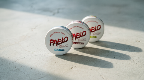 Three PABLO nicotine pouch cans in a row on a concrete worktop