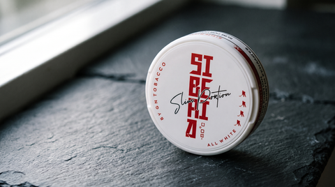 White circular tin with red Shiro branding sitting on dark slate surface near window