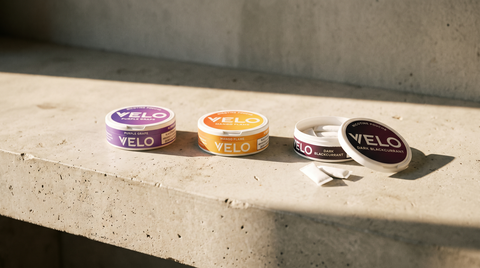 Three VELO nicotine pouch cans in different flavours arranged on a concrete worktop, one open