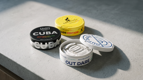 Three nicotine pouch cans on a pale concrete worktop, one open showing white pouches inside