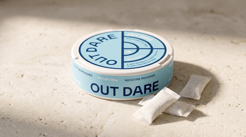 OutDare nicotine pouch can with loose white pouches on a limestone surface