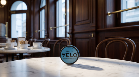 A round nicotine pouch can on a marble café table inside a European brasserie