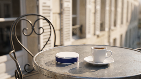 Round nicotine pouch can beside an espresso cup on a zinc bistro table in France