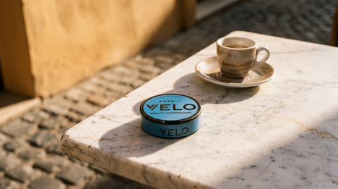 A nicotine pouch can on a marble Italian café table beside an espresso cup