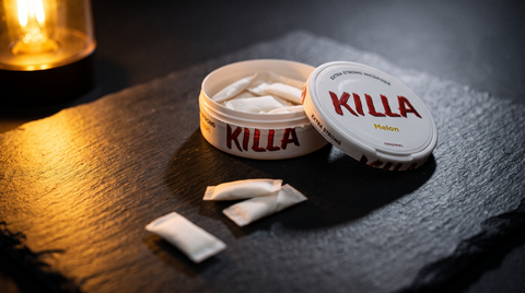 Open nicotine pouch can with white pouches visible, lit by dramatic warm amber light on dark slate