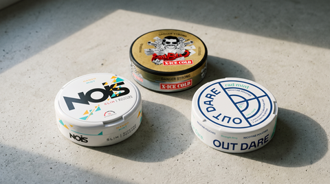 Three nicotine pouch cans from different brands grouped on a pale concrete worktop
